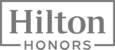 The image shows the logo for "Hilton Honors," displaying the brand name in a stylized font within a rectangular frame.