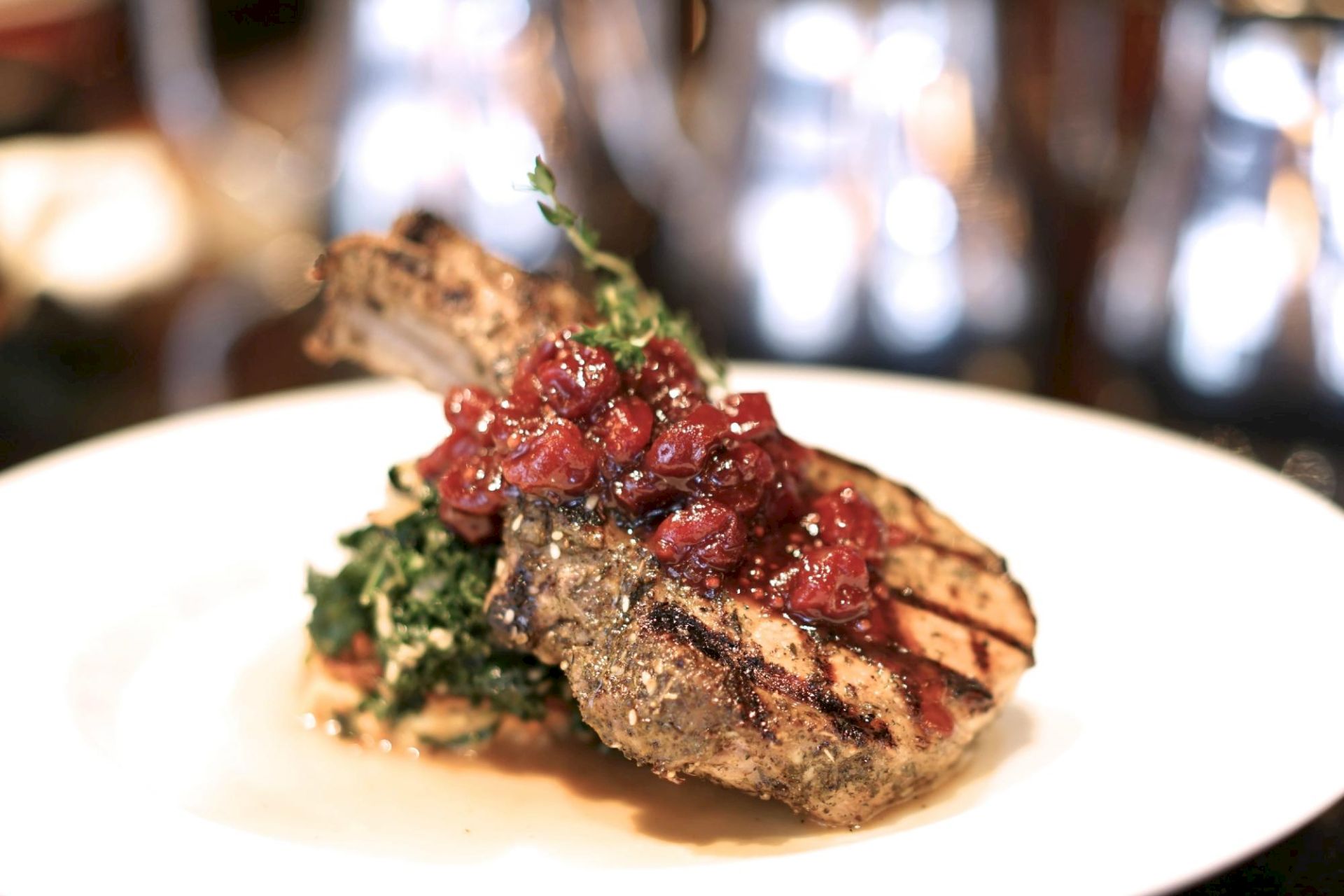 Grilled meat chops with a topping, garnished with herbs and served on a white plate.