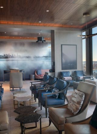 A modern lounge features plush seating, large windows with a scenic view, wooden ceiling, and contemporary decor.